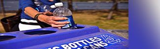 This is a picture of someone putting a plastic bottle into a recycling bin.