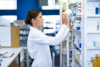 This is a picture of a pharmacist looking through a shelf of medicine