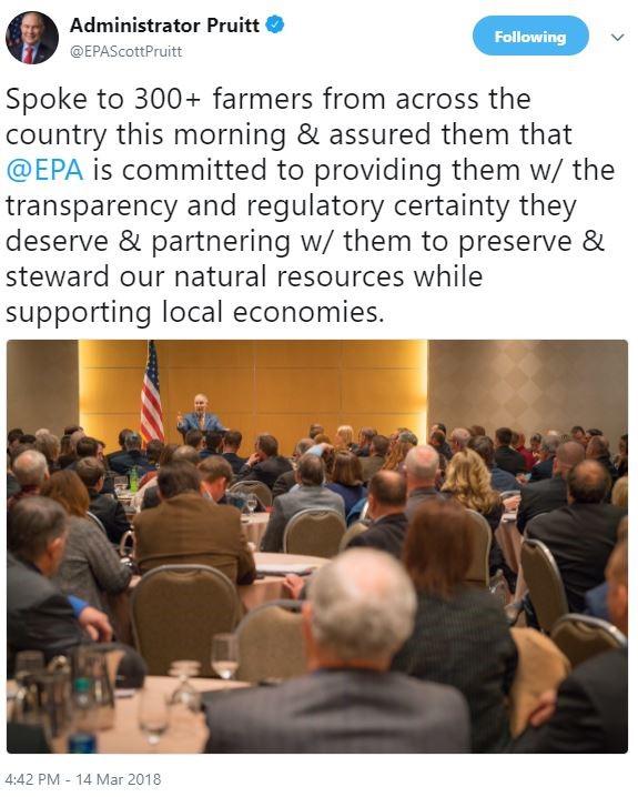 Admin speaking at podium to hundred people seated at round tables