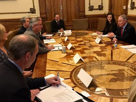 Admin. Pruitt sits at a large wooden conference table across from Indiana Governor Eric Holcomb. They are joined by six other people at the table including Lt. Governor Suzanne Crouch and other state officials.