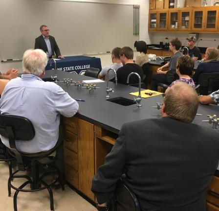 Wheeler addressing student from podium.