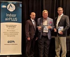 Three men stand on a stage next to an Indoor airPLUS sign