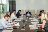 Scott Pruitt sits at the head of a conference table while he and others seated around it read