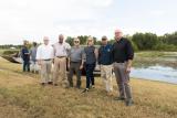 Several people stand in front of a pond