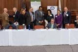 Acting Administrator Wheeler seated at a long table signing a paper with onlookers