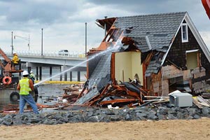 Contractors maintain a spray of water on a home for dust control during the demolition process.