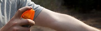 Applying insect repellent spray to arm