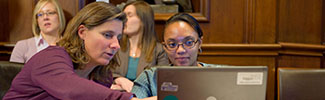 Decorative photograph of an instructor reviewing infomation on-screen with a student
