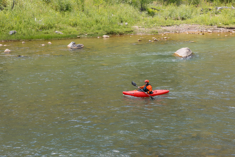 a person in a red kayak on a wilderness river