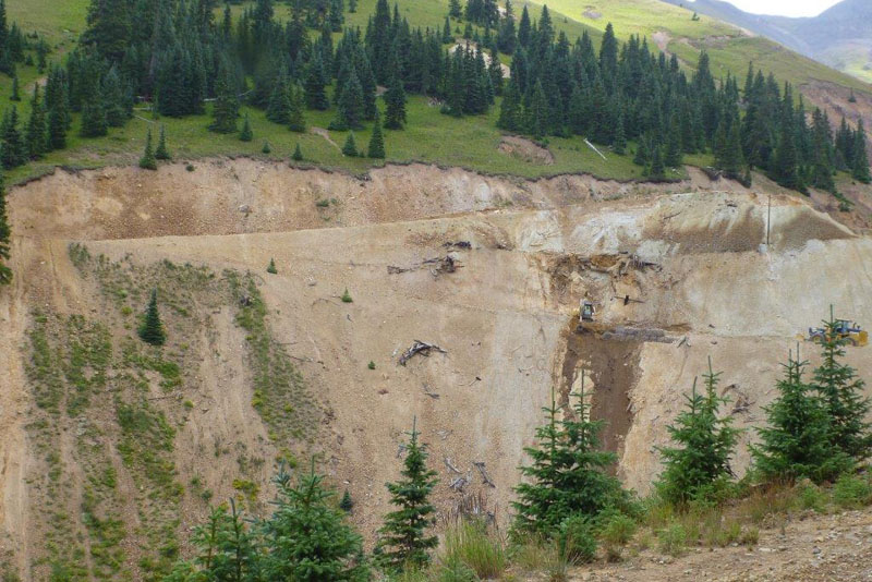 Looking across a vally, the opposite slope is a mostly dirt face with roads cut diagonally.