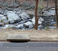 Photo of a sewage drain in a rocky forested area.