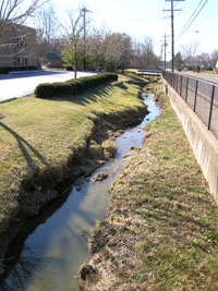 Photo showing a stream cut between two road embankments as a result of runoff. 
