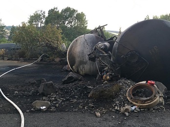 Close up photo of derailed train cars leaking crude oil.