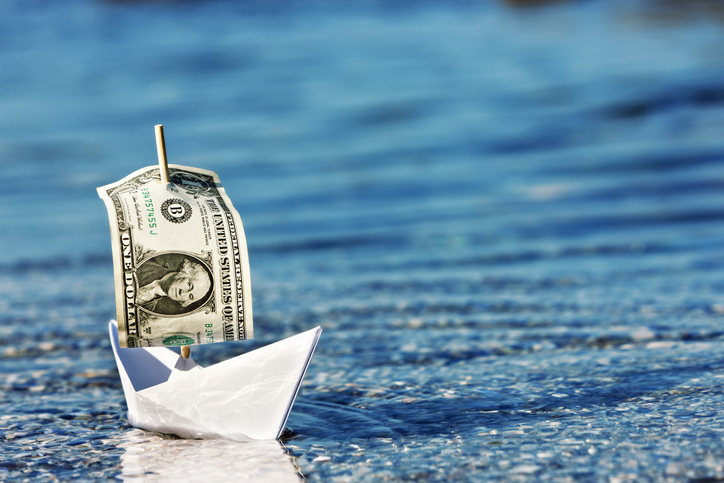 Paper boat with dollar bill for a sail