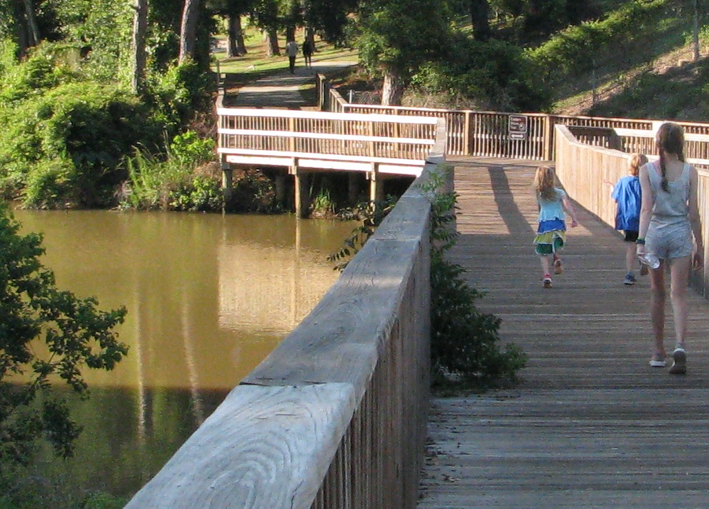 People enjoying nature and walking along a boardwalk at Mobile Bay National Estuary in Mobile, Alabama.