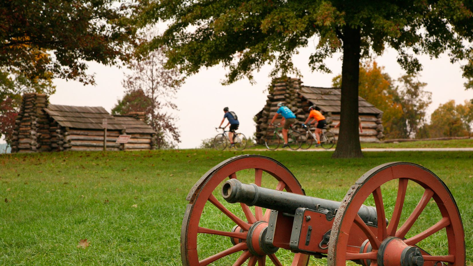 Photo of Valley Forge National Historic Park with people bicycling next to historic homes and a cannon