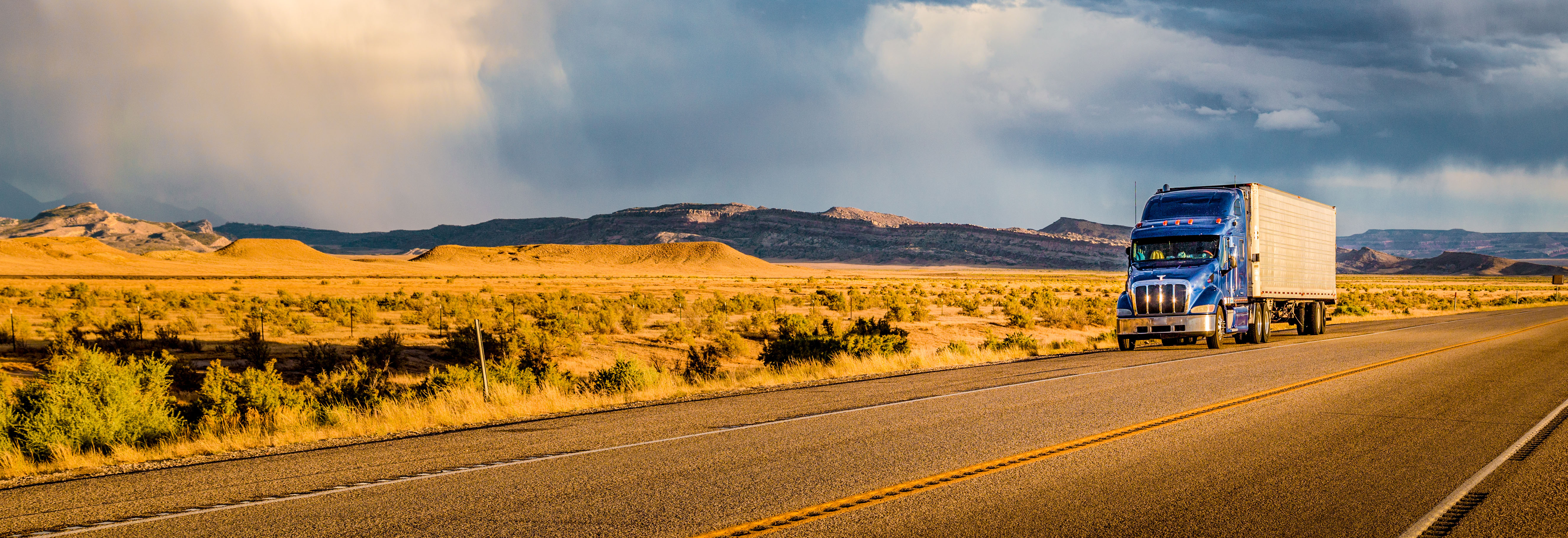 Truck on highway, golden fields, clouds, and sunny skies
