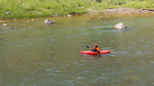 a person in a red kayak on a wilderness river