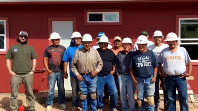Workers standing in front of a  completed home.