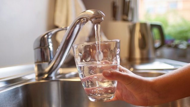 child getting water from faucet