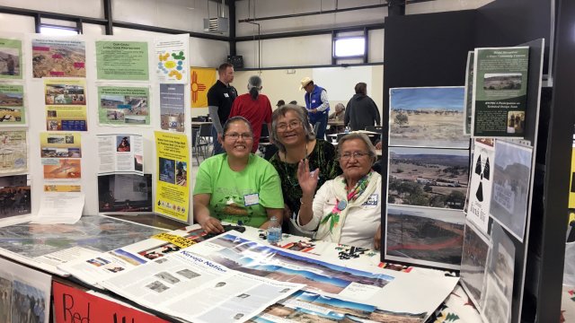 Three woman sitting at information booth table