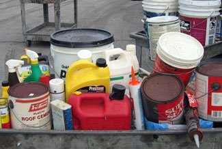 Construction materials, including caulk, gas can, roof cement, paint, in a wheelbarrow