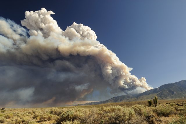 Wildfire smoke rises over some hills in California