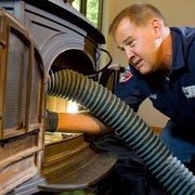 Chimney sweep conducting an inspection of a wood stove