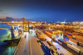 Port with docked container ship, cranes and container yard.