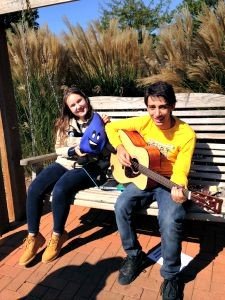 Two kids sitting on a bench playing guitars