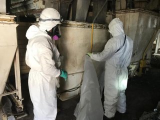 Asbestos removal contractors placing plastic sheeting for containment purposes. 
