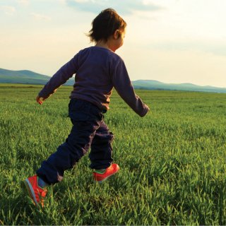 Young boy running through a grassy field.