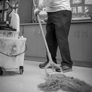 Man mopping the floor in a classroom.