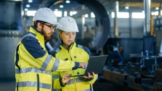 two people in hardhats looking at computer