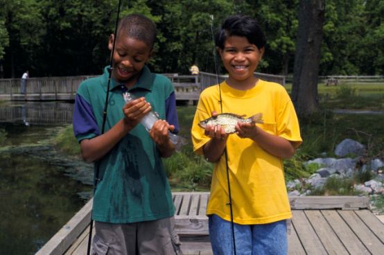 Two boys holding small fish that they caught