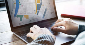 Person typing on an laptop with a map on the screen