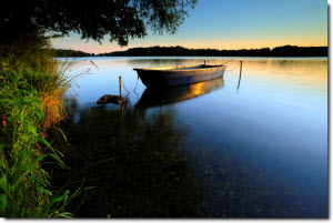 wooden boat tied to the shoreline at sunset