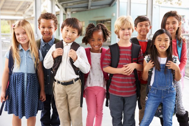 Un grup de copii se află în fața școlii