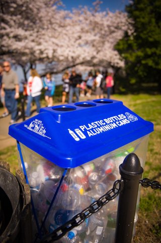 Woman recycling plastic in blue bin