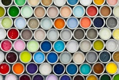 An overhead view of tightly packed rows of open paint cans in a variety of colors.