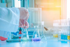 A scientist uses a pipette to drop chemicals into a beaker