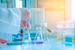 A scientist uses a pipette to drop chemicals into a beaker 