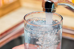 A faucet filling a glass with clear water