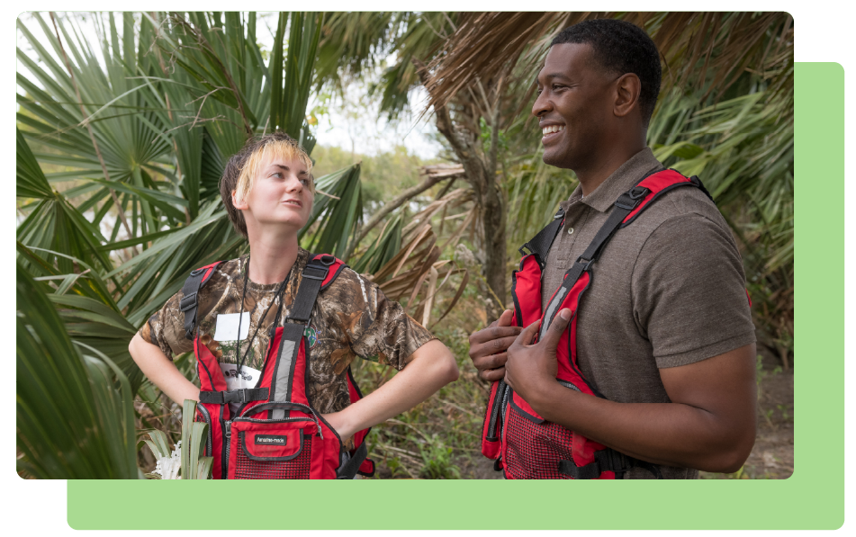 A man and woman in a tropical location looking forward at a path. 