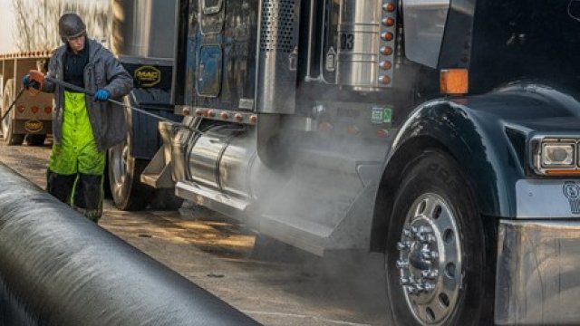 Individual powerwashing a truck leaving the site