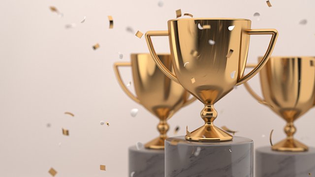 Golden trophy award with falling confetti on grey background
