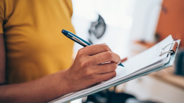 Person holding a clipboard with paper