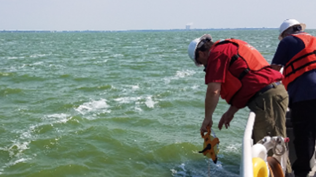 Two EPA scientists collecting water samples of Lake Erie from a boat.