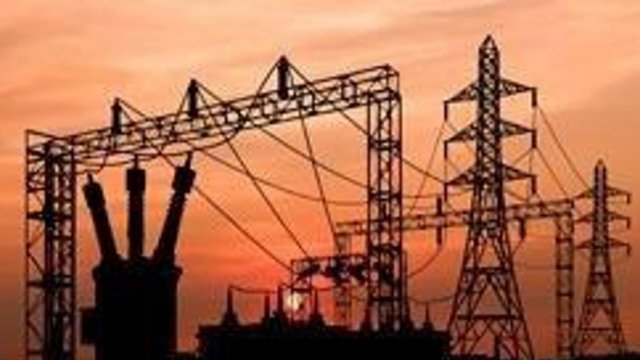 Power lines and transformers with an orange sky in the background
