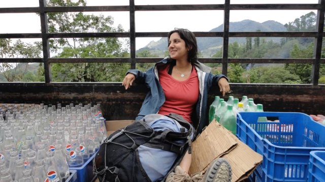 Sheila Xiah Kragie sitting amongst bottles for recycling; mountains in the background